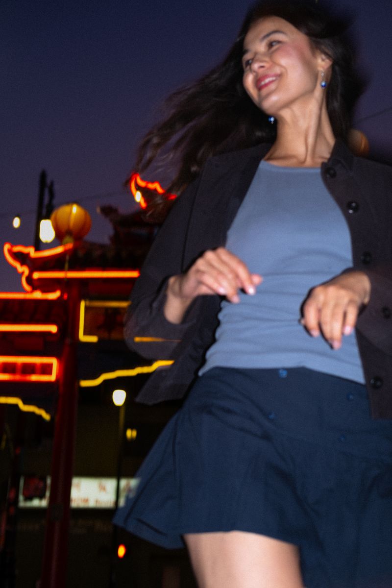 Woman mid-motion, dancing beneath red and green neon lights