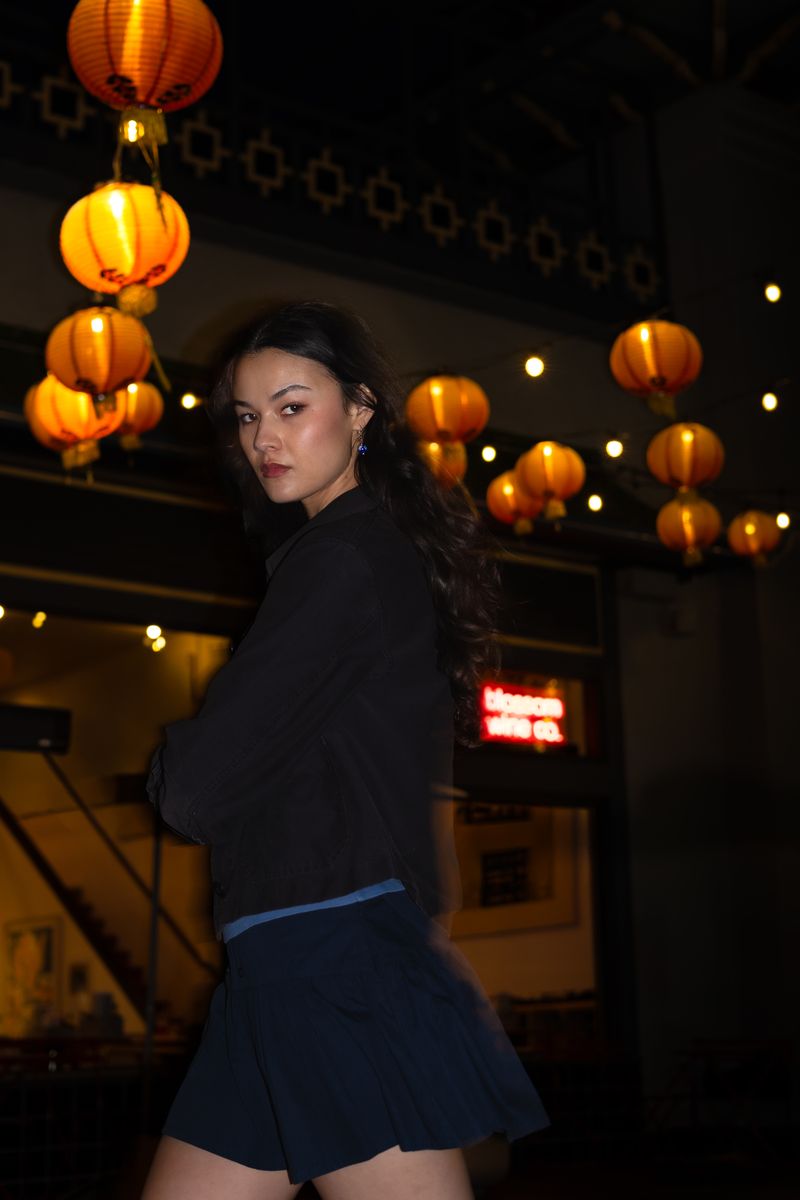 Woman walking past glowing neon signs and red paper lanterns at night