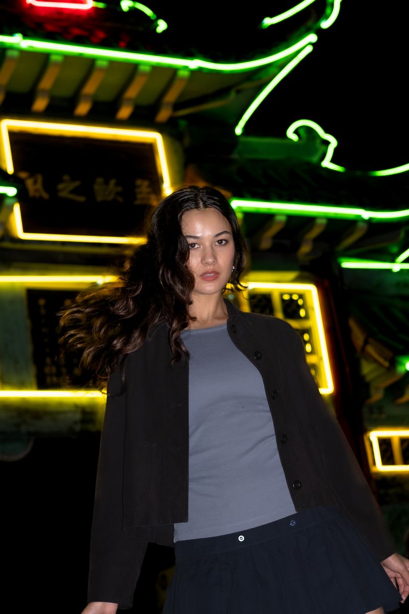 Woman standing beneath a glowing neon sign at night