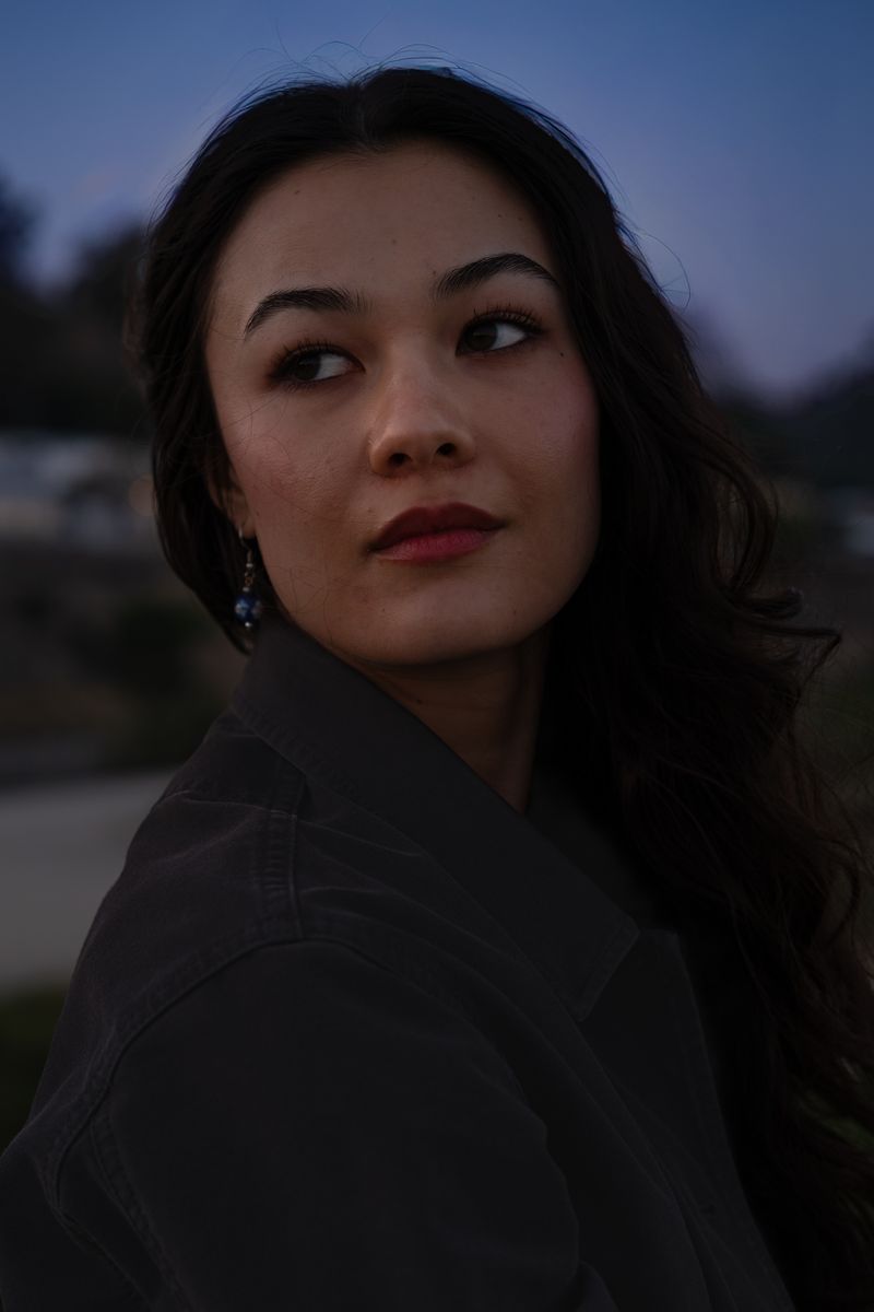 Woman looking over her shoulder against a darkening dusk sky