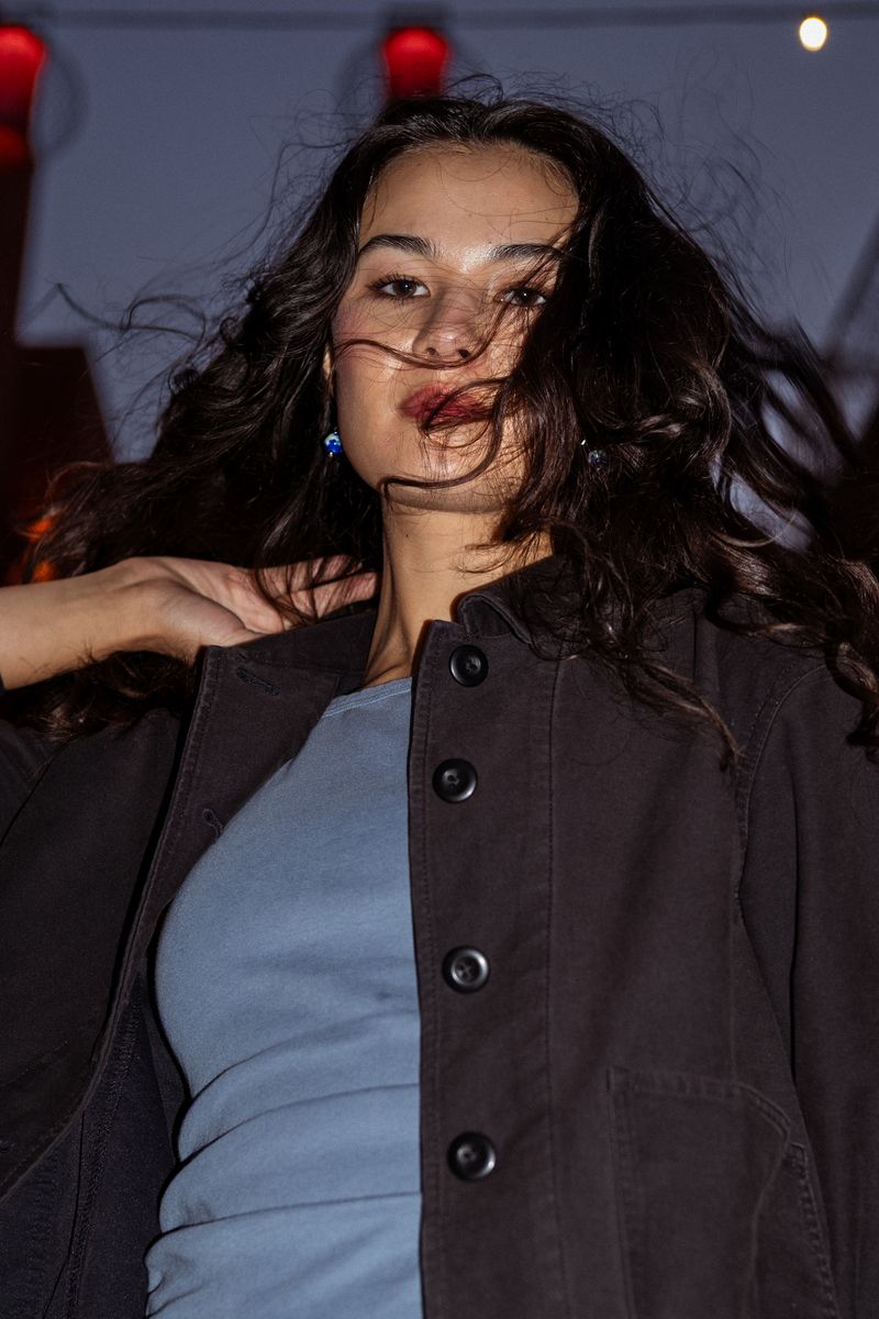 Close-up portrait of a woman, hair blown across her face in dusk light