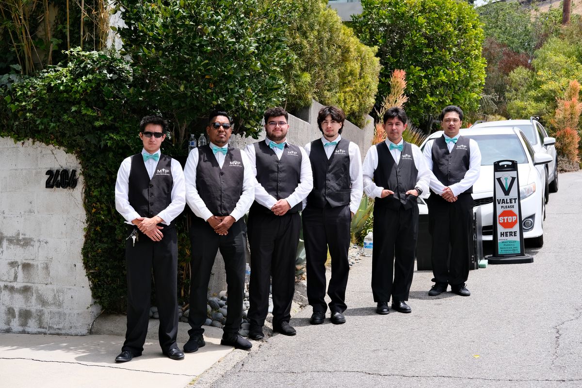 A row of catering staff in vests lined up outside on the street