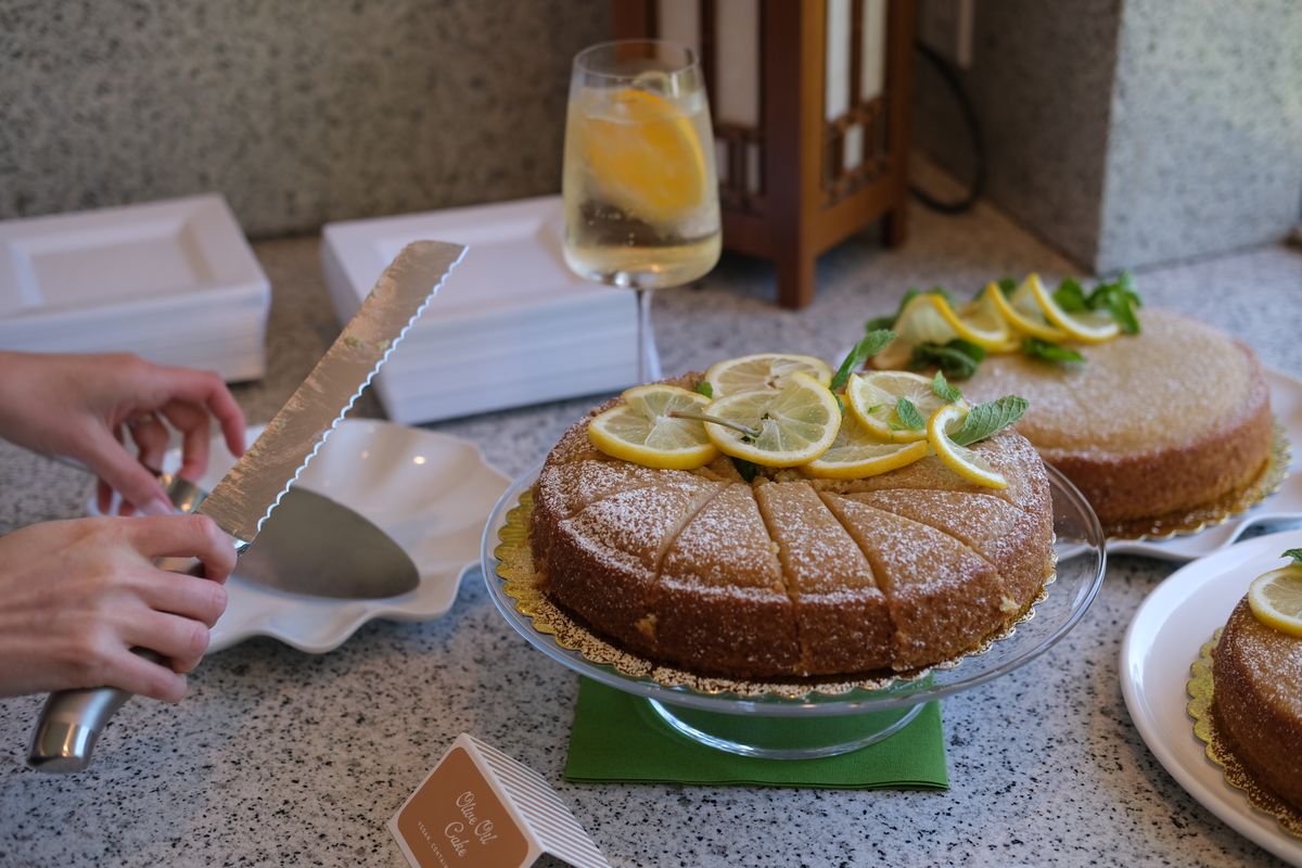 A citrus cake being sliced on a marble counter