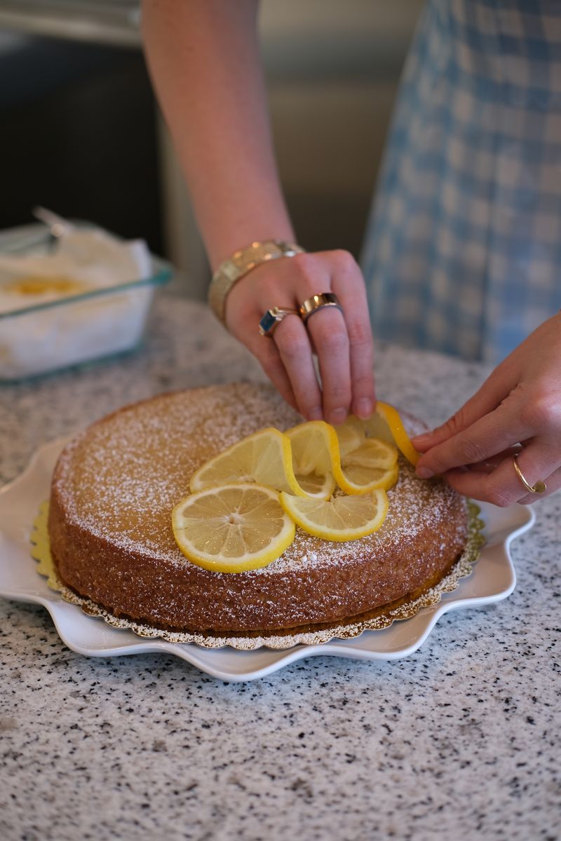 Close-up of hands arranging lemon slices on a cake
