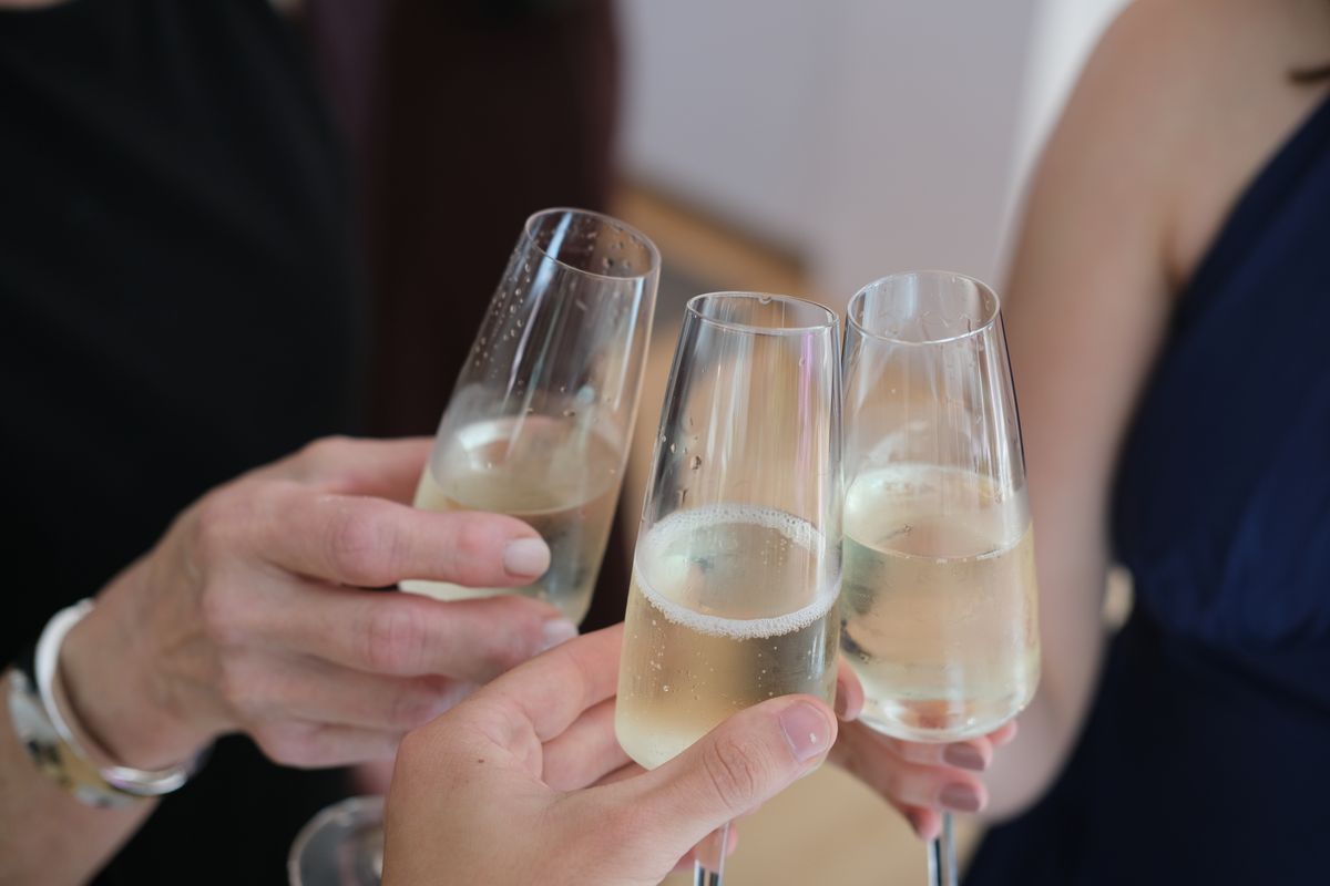 Close-up of hands clinking champagne glasses