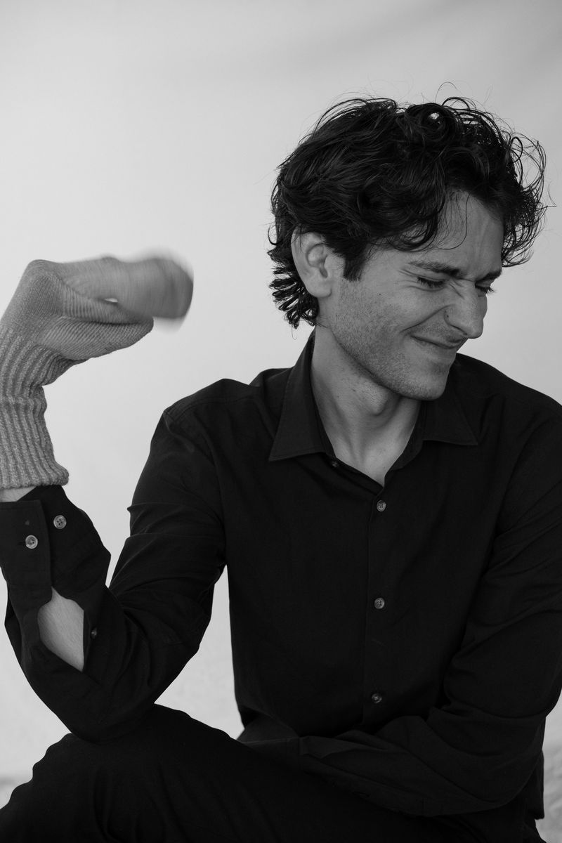 Black-and-white portrait of a man with his arm raised, laughing