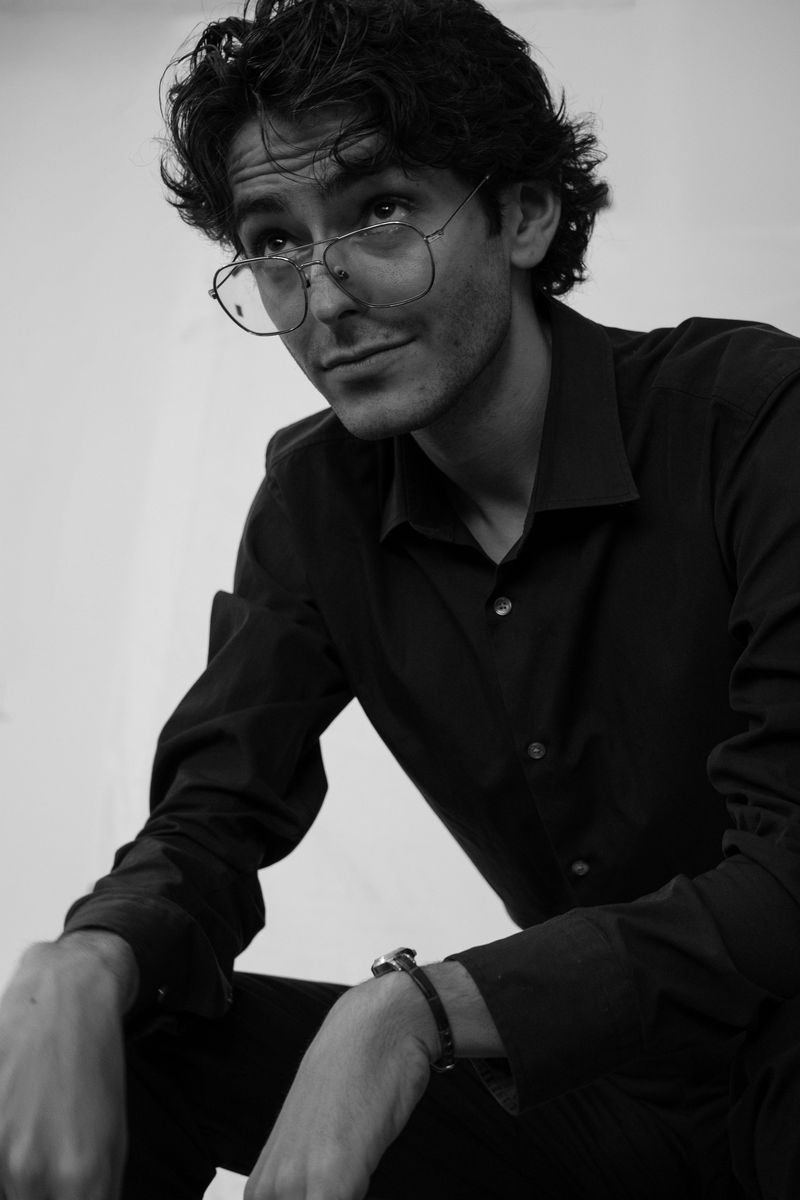 Black-and-white portrait of a man with tousled hair, seated