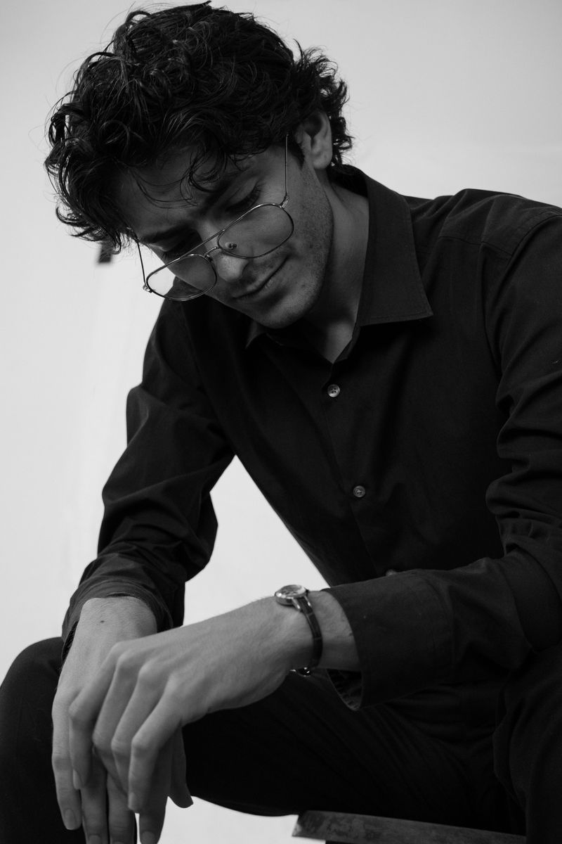 Black-and-white portrait of a man resting his chin on his hand, looking down