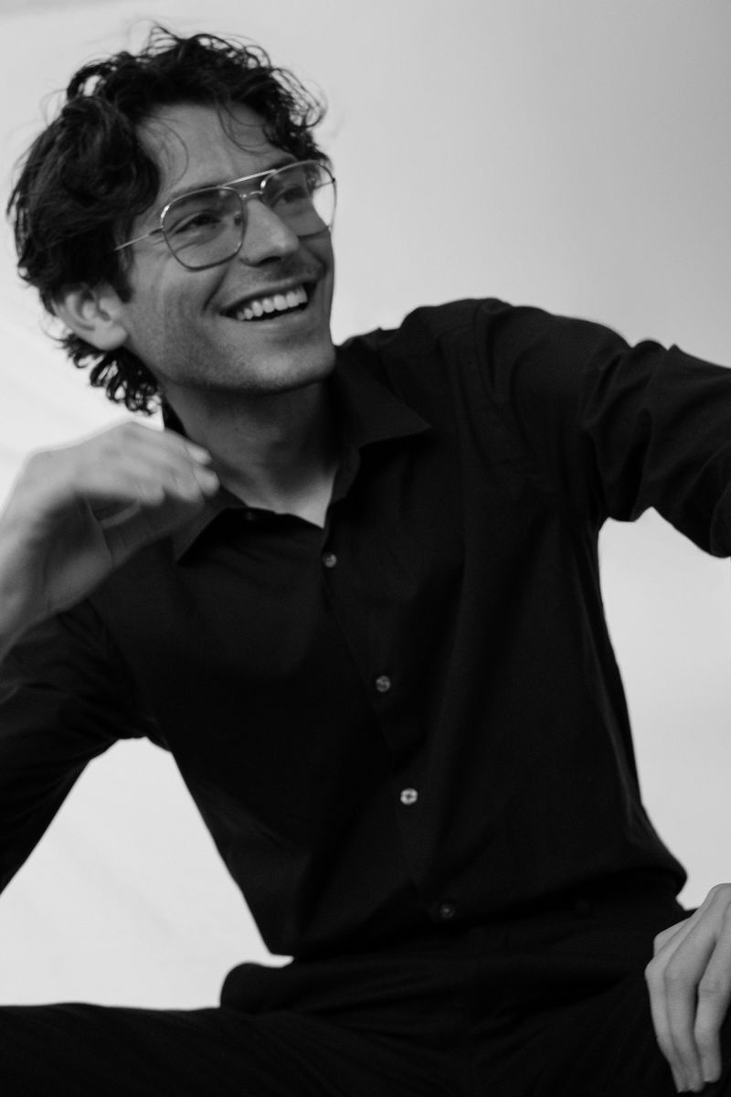 Black-and-white portrait of a man laughing with his arm outstretched