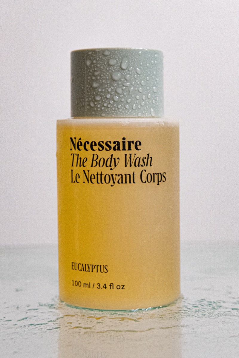 Nécessaire body lotion and body wash bottles styled on a wet surface