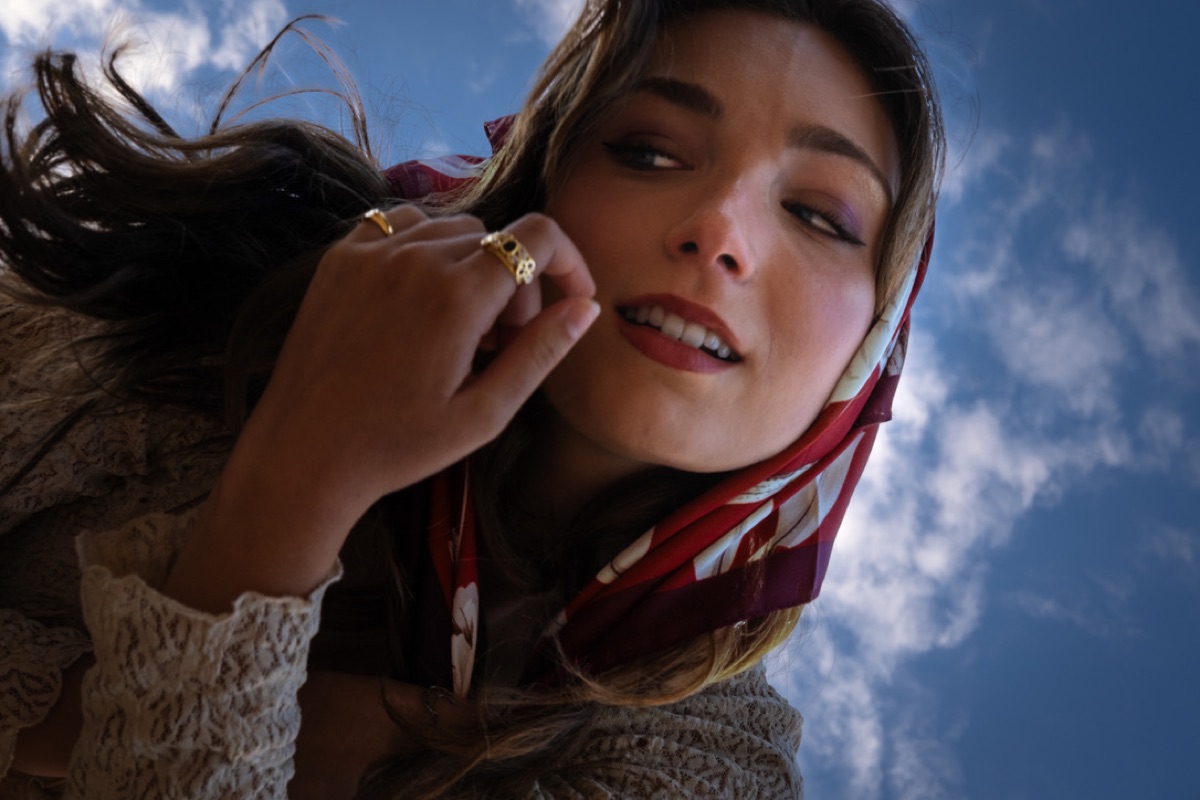 Portrait of a woman in a red scarf looking up at a blue sky, from the Madelaine portrait series