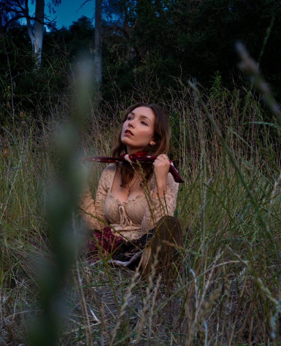 Portrait of a woman seated in tall grass at dusk, from the Madelaine portrait series
